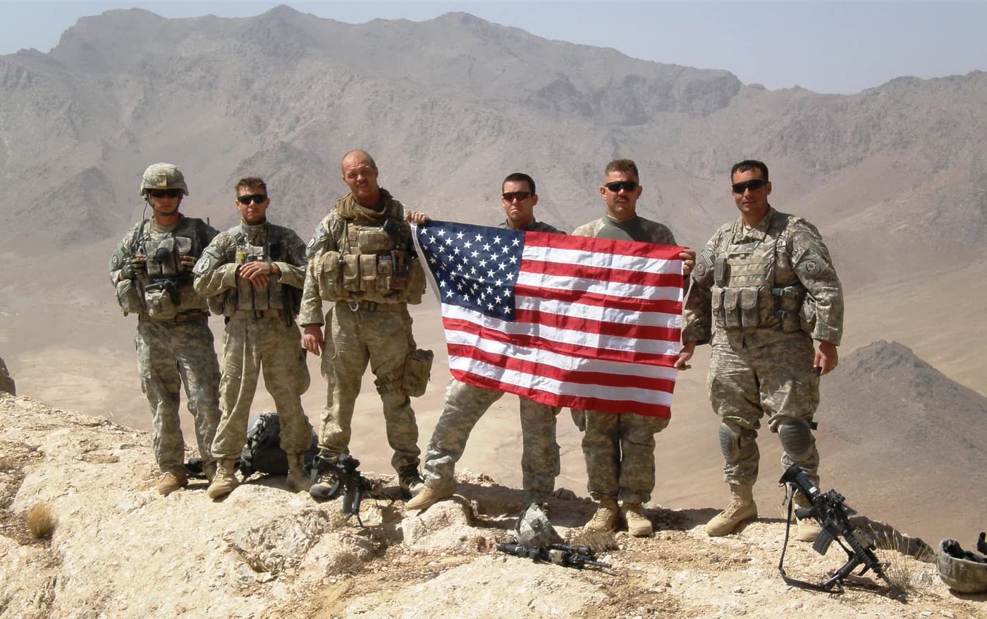 Veterans holding the American flag on a mountaintop