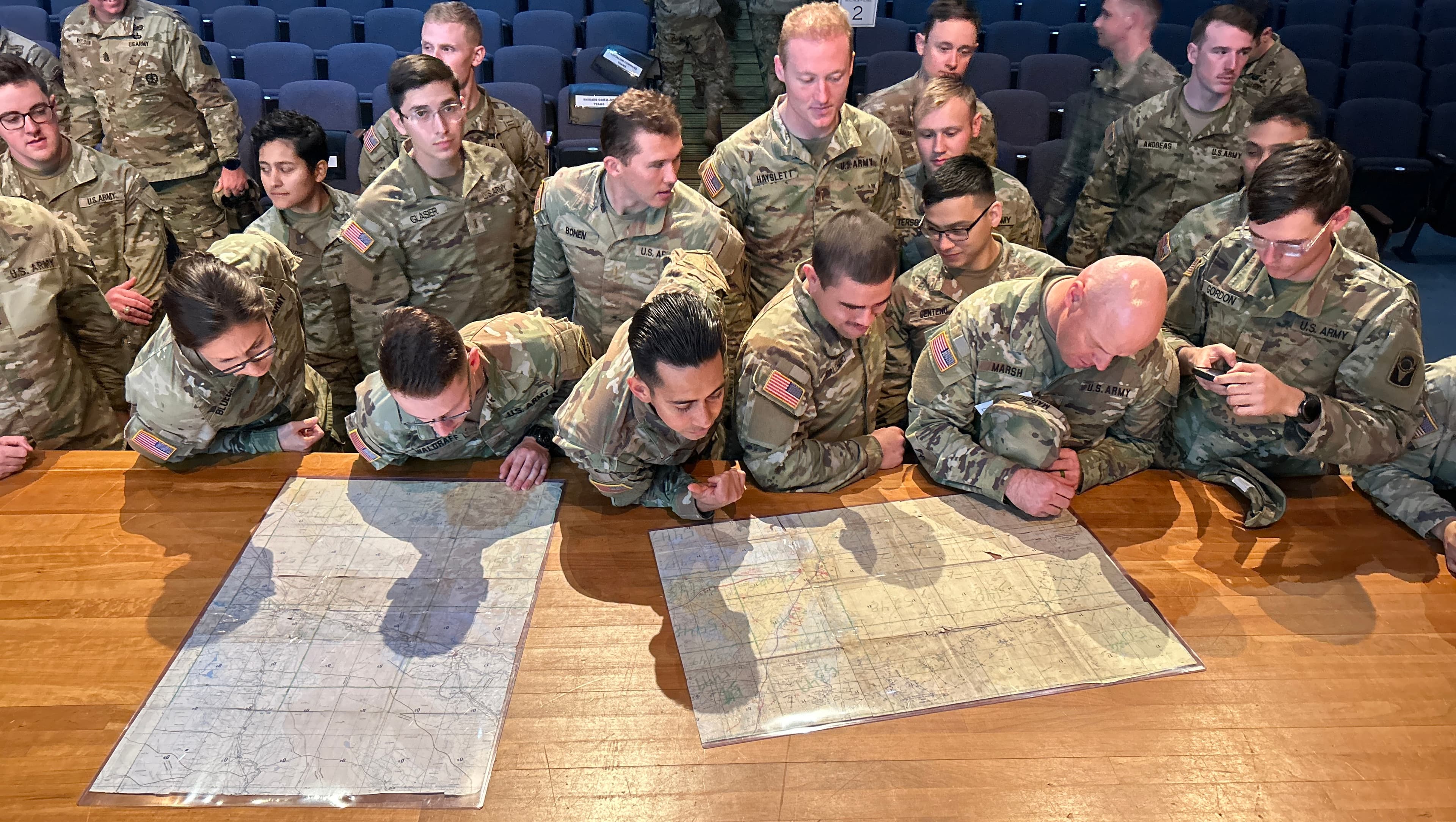 U.S. Army soldiers studying tactical maps spread across a table during a planning session