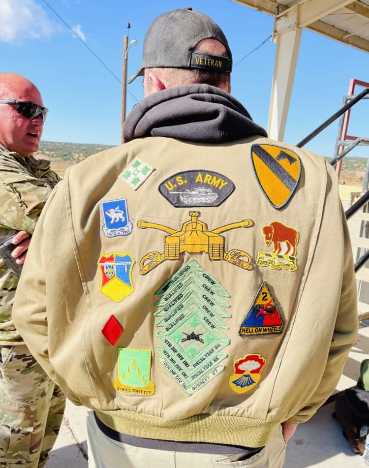 A Veteran's jacket covered in decades of earned unit patches — 1st Cavalry, 2nd Armored Hell on Wheels, crew qualification badges, division crests, and more
